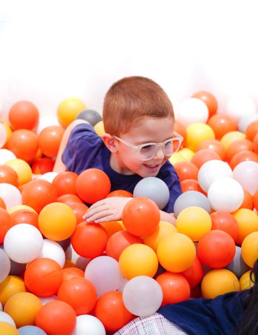 A boy playing in a colorful ball pit.