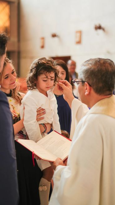 Child being blessed by a priest during a ceremony.