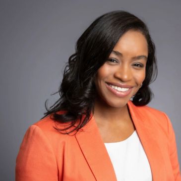 Professional woman in an orange blazer smiling.