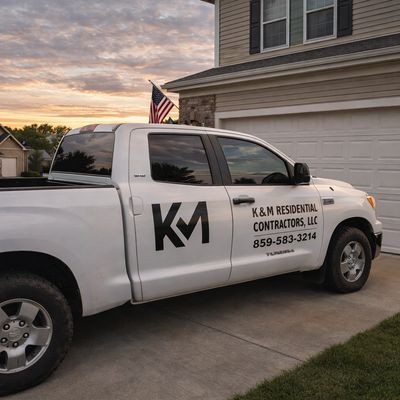 White truck with K&amp;M Residential Contractors logo parked outside a house.
