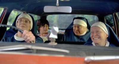 Four nuns and a child inside a car, with the driver focused and others looking amused.