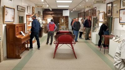 Visitors explore a museum exhibit filled with vintage items and framed pictures.