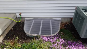 Egress window well covered with a frosted polycarbonate custom-fit cover for safety and insulation