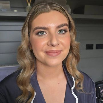 A young woman with wavy blonde hair and natural makeup smiles at the camera.