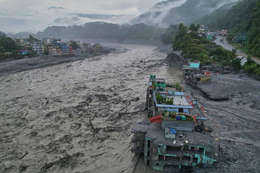 Flooded river with damaged buildings on its banks.