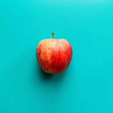 a red apple on a turquoise background