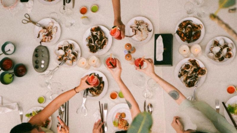 Overhead view of table with arms outstretched with wine glasses