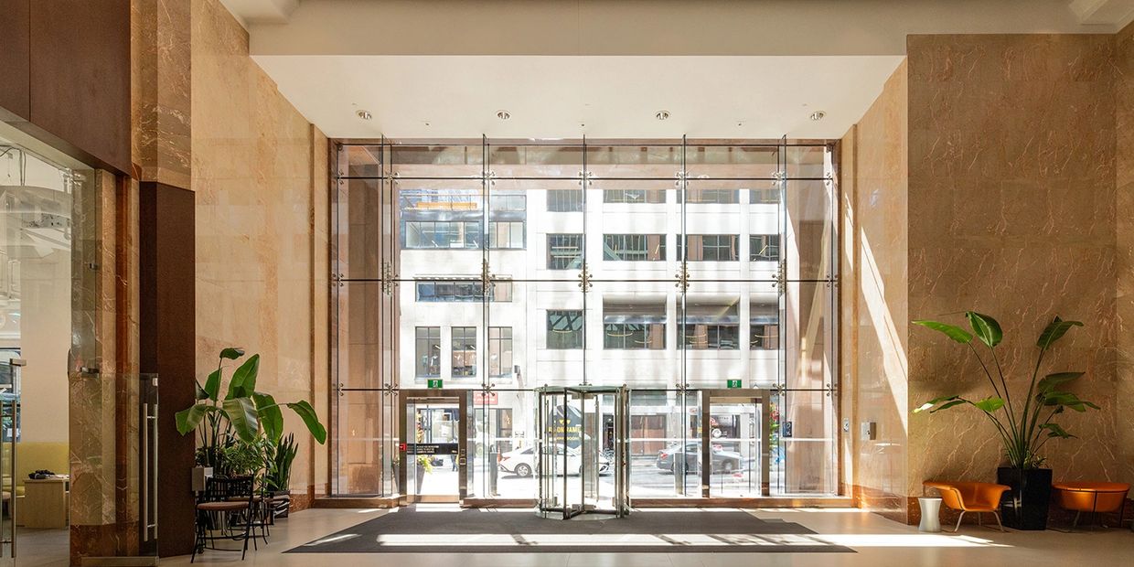 All-glass entrance system in a high-ceiling lobby space looking out to the street.
