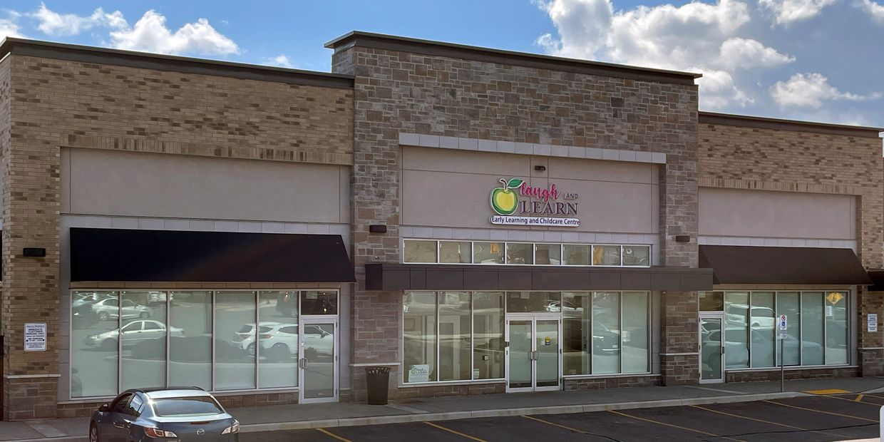 A retail plaza with prominent signage for a childcare centre with large window areas.