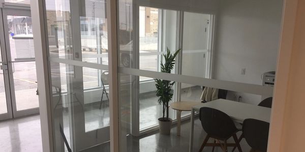 Glass enclosed office overlooking a glass entry door and parking lot beyond.