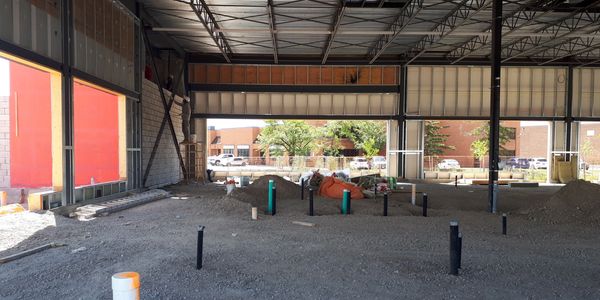 Construction photo of the childcare unit in the retail plaza building with plumbing pipes visible.