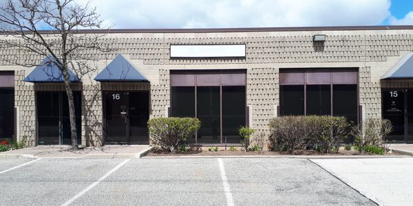 A photo of a one story split face masonry building with blue triangular awnings.