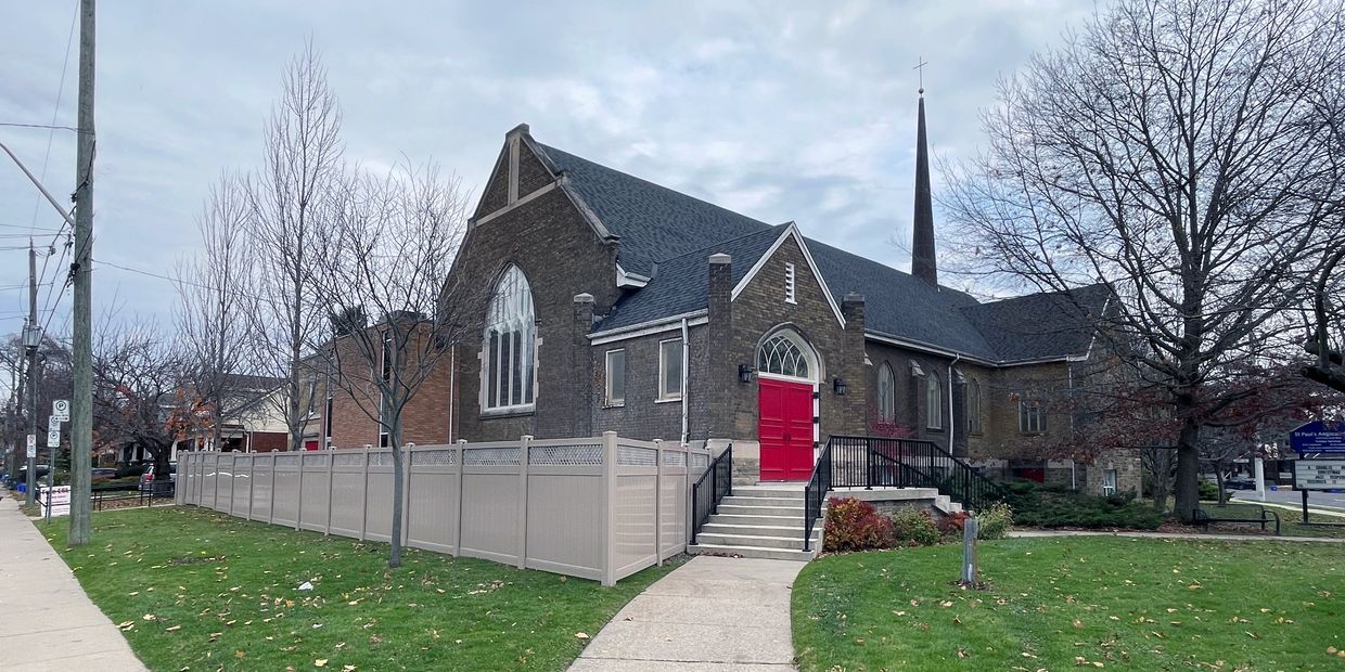 An historic church with mid-century community hall and fenced landscape.