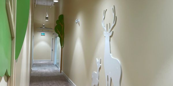 Corridor with painted millwork wall panels cut in shapes of deer and trees.