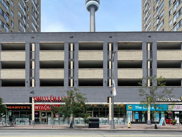 Urban retail podium of stores and upper parking garage with Toronto's CN Tower in background