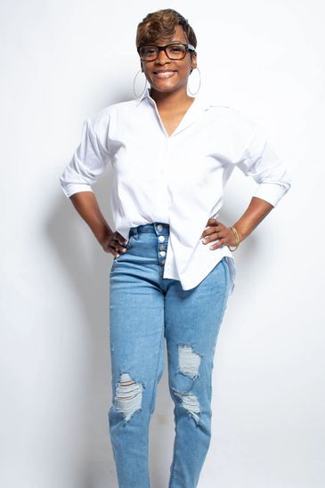 Woman in white shirt and ripped jeans smiling.