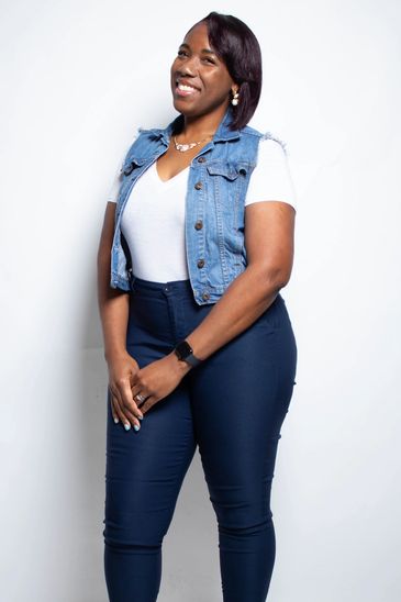 Smiling woman in denim vest and white shirt.