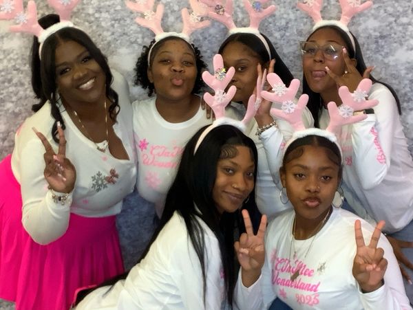 Group of women wearing pink antler headbands making peace signs.