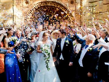 Bride and groom exiting with confetti and cheering crowd.