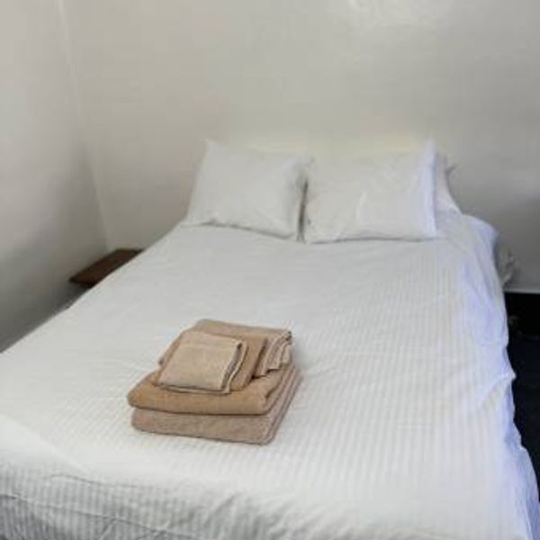 Neatly made bed with white linens and folded beige towels.