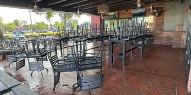 Chairs stacked upside down on tables in an empty outdoor patio.