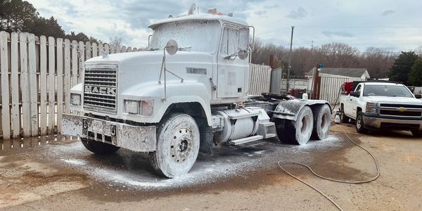 A large white truck covered in foam during a wash.