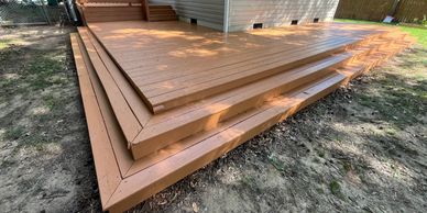 Wide wooden deck with multiple step levels around a house.
