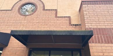 A black awning over a doorway with the number 102 on a brick building.