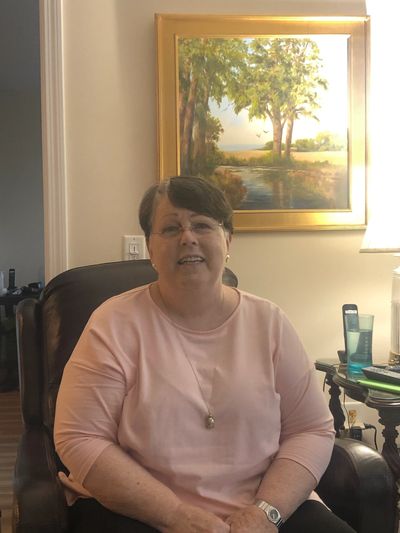 A woman smiling while sitting in a leather chair indoors.