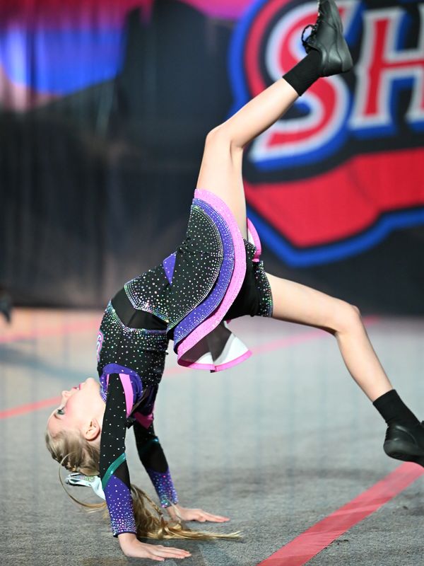 Young cheerleader performing a backbend during a routine.