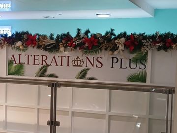 Sign for Alterations Plus decorated with festive garland.