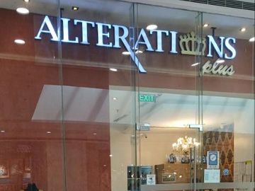 Glass storefront of Alterations Plus with a mannequin and sewing machine inside.
