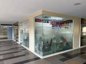 Glass-walled alterations shop with sewing-themed artwork and neat interior.