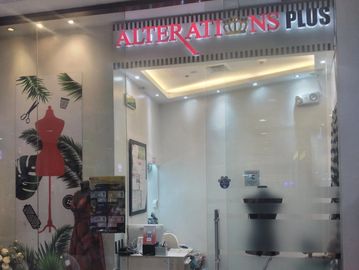 A modern alterations shop with glass walls and mannequins.