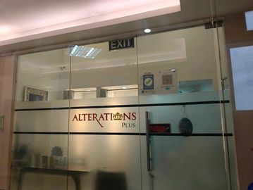 Glass door of a tailoring shop named Alterations Plus with push sign.