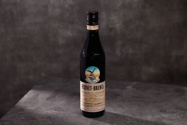 A bottle of Fernet-Branca on a gray surface.