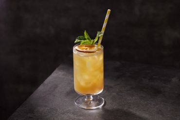 Iced tea in a tall glass with a mint garnish.