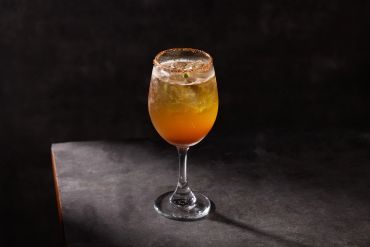 Elegant cocktail in a wine glass with ice and garnish.