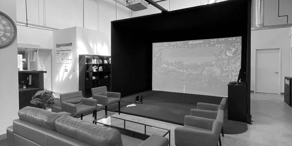 Indoor golf simulator lounge with seating.