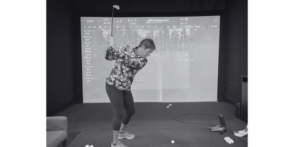 Person practicing golf swing indoors with simulator.