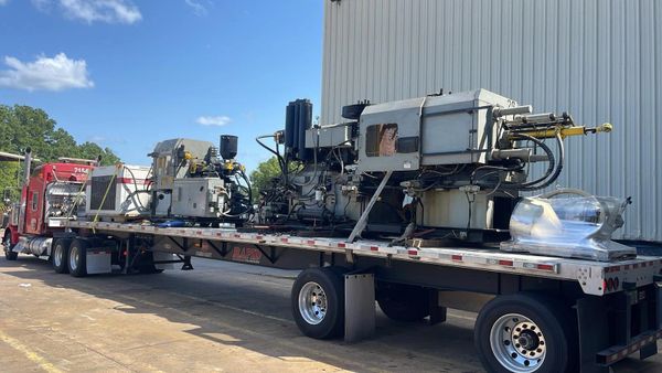 Heavy machinery loaded on a flatbed truck under a clear blue sky.