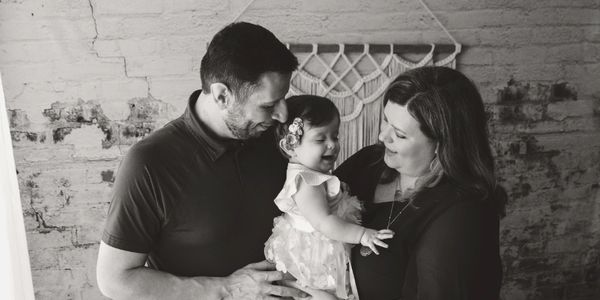 Black and white photo of parents holding their smiling baby.