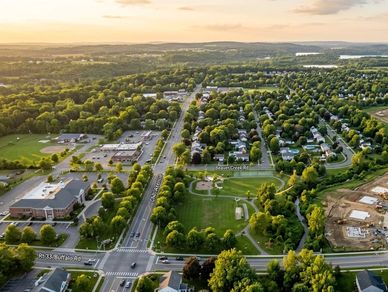 Aerial view of a suburban neighborhood with parks, roads, and new housing developments.