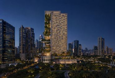 Modern skyscraper with integrated greenery illuminated at night in a cityscape.