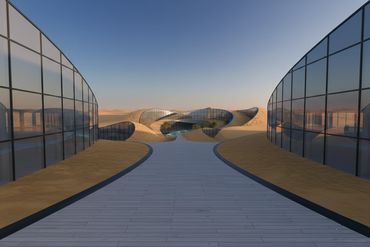 Modern glass buildings with curved sandy mounds and a central pathway under a clear sky.