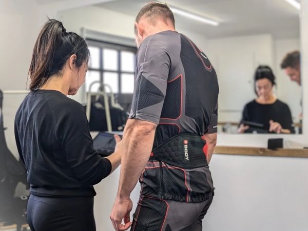 Trainer and athlete reviewing progress on a tablet in a gym setting.