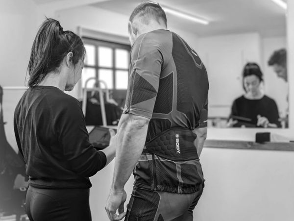 Trainer and athlete reviewing progress on a tablet in a gym setting.