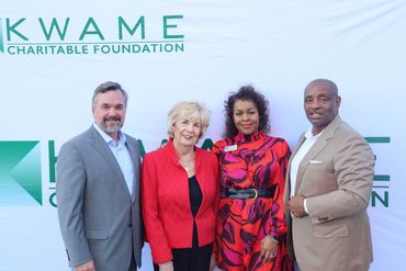 Four people posing at a Kwame Charitable Foundation event.