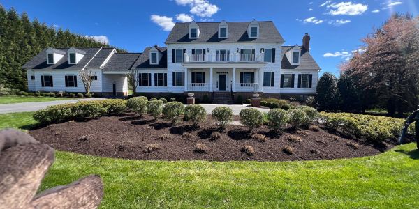 Large white house with dormer windows and manicured garden.