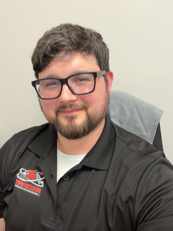 Smiling man wearing glasses and a work shirt.